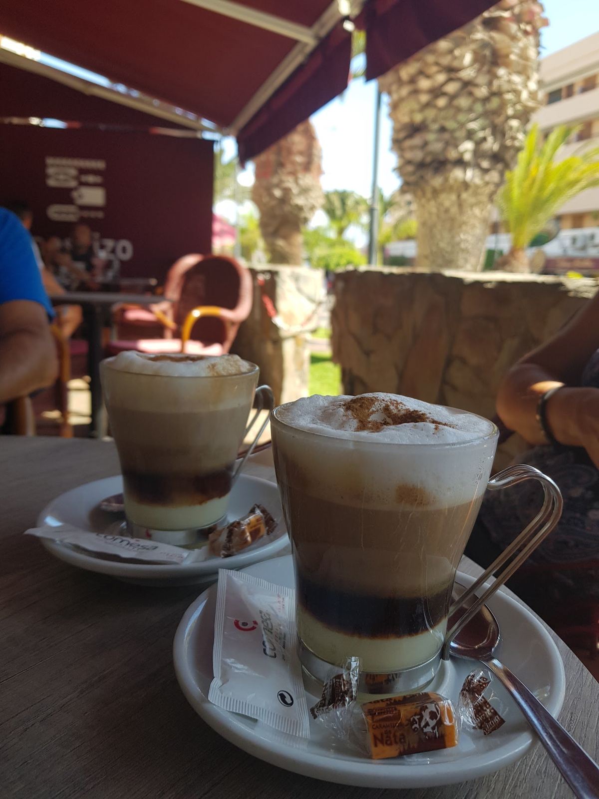 Dos cafés en vaso con leche, café y espuma sobre una mesa de la terraza